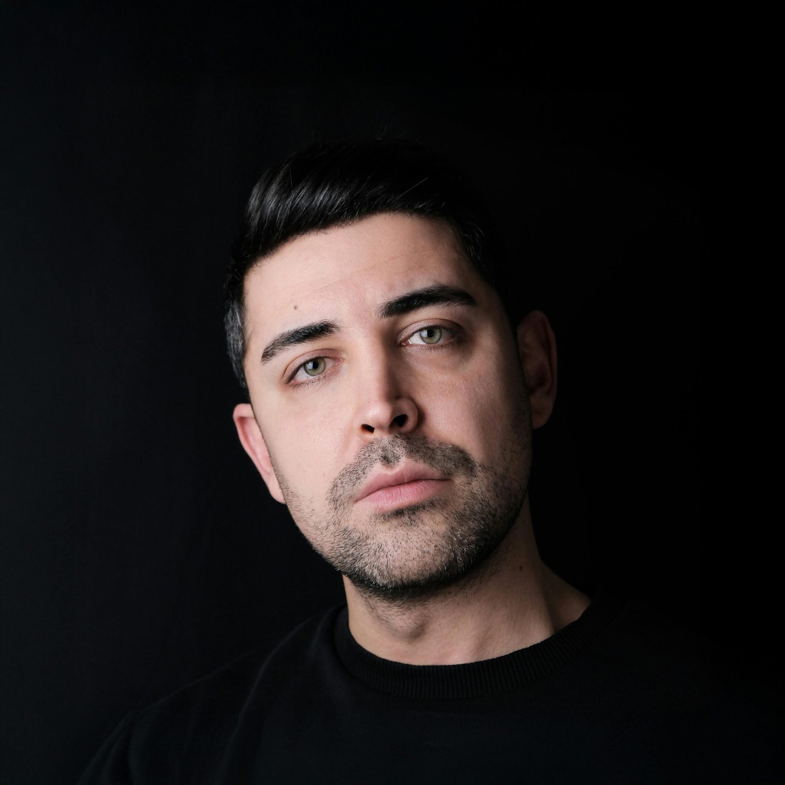 Close-up portrait of a contemplative young man against a dark background.